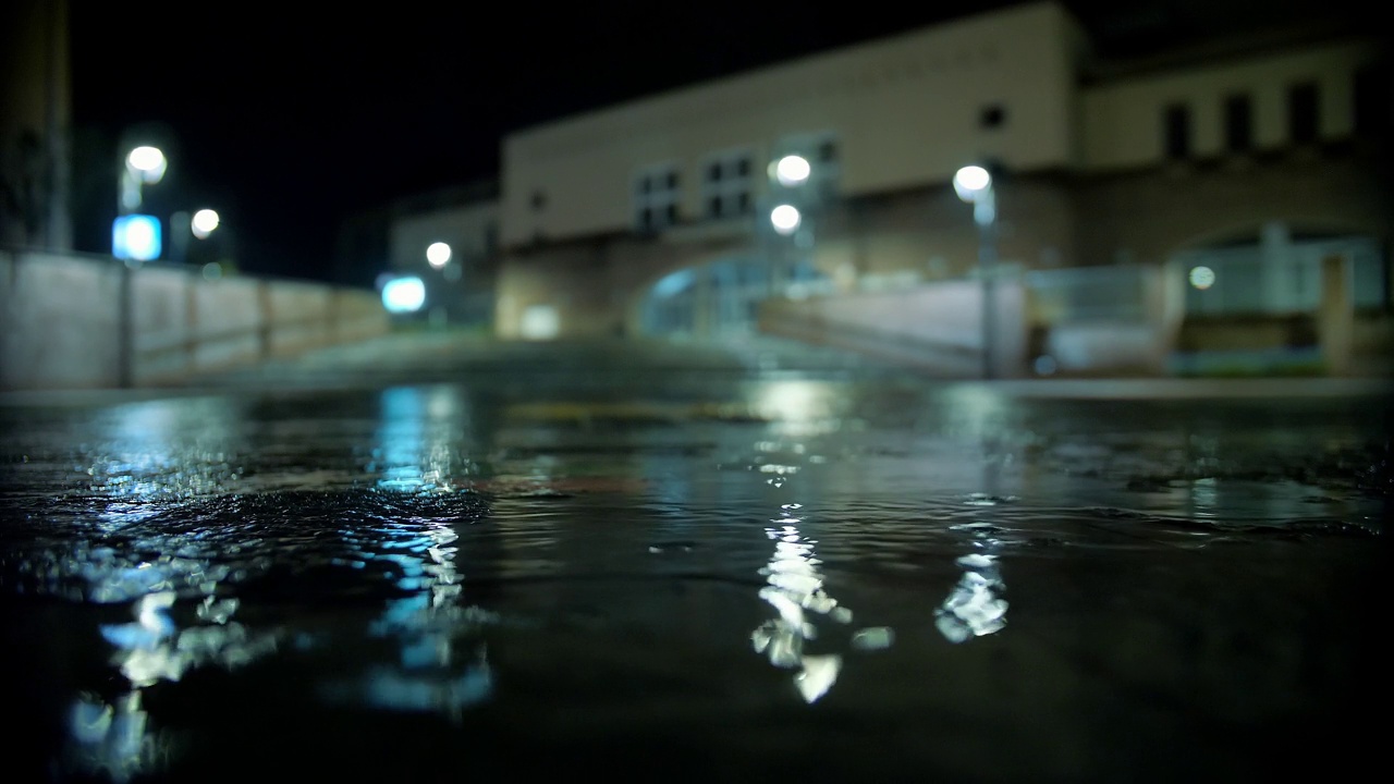 下雨了。一滩水。夜晚的城市。雨滴与路灯。视频素材