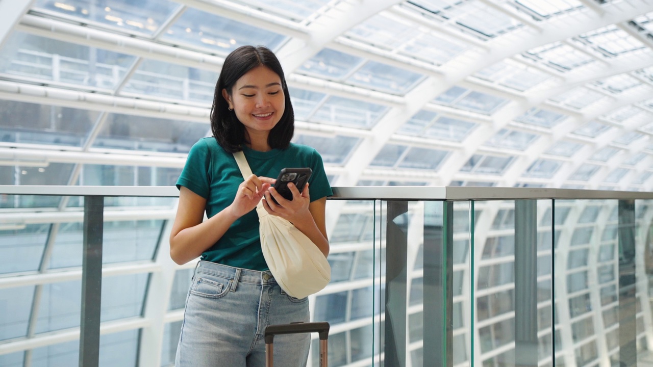 玩手机通讯，在候机楼内等候登机的女子旅行。视频素材