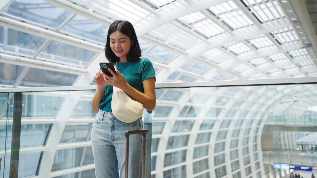 玩手机通讯，在候机楼内等候登机的女子旅行。视频素材