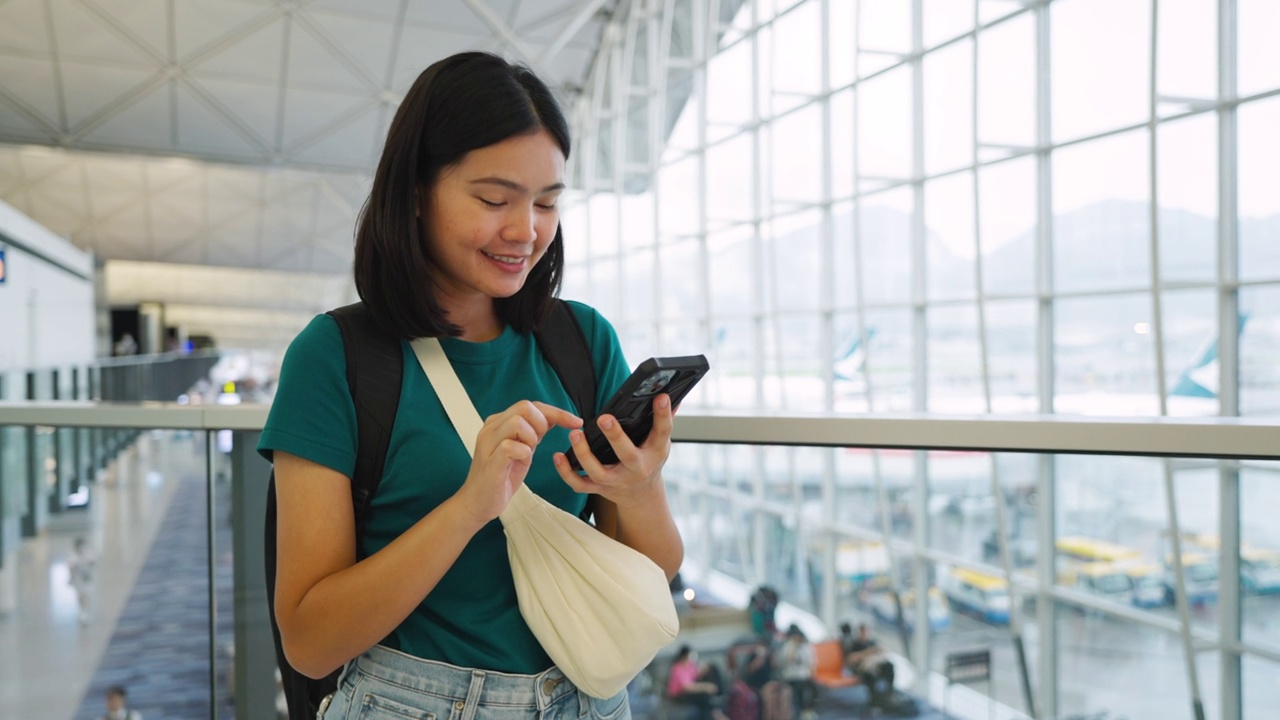 玩手机通讯，在候机楼内等候登机的女子旅行。视频素材