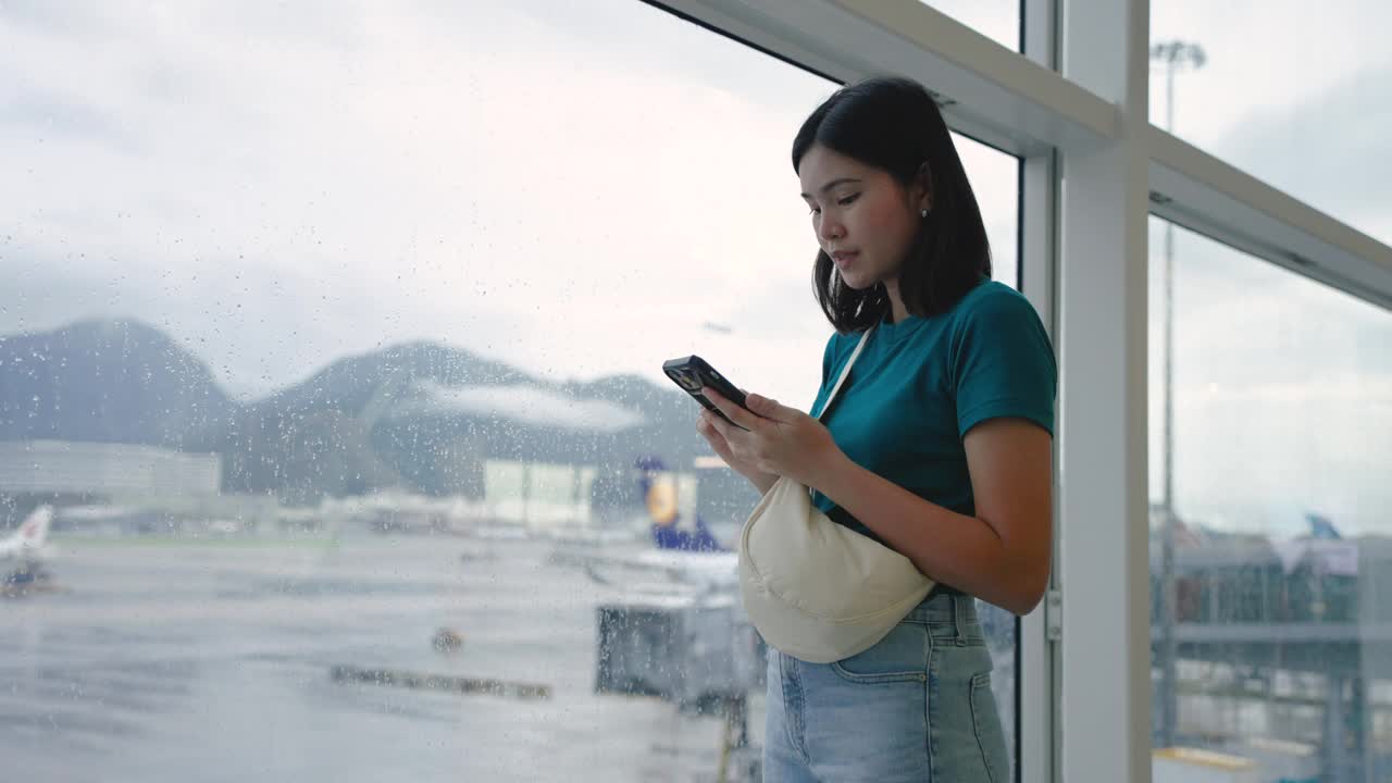 玩手机通讯，在候机楼内等候登机的女子旅行。视频素材