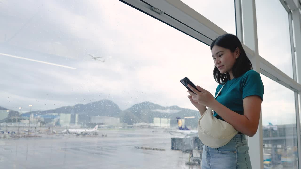 玩手机通讯，在候机楼内等候登机的女子旅行。视频素材