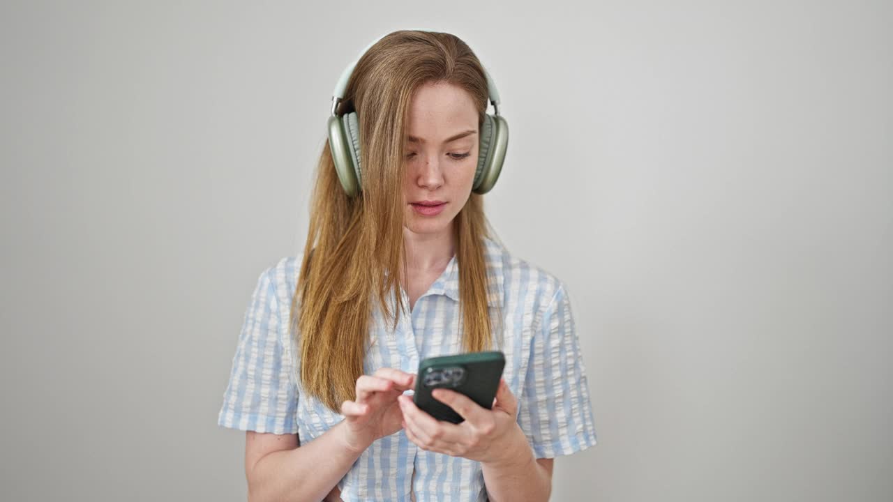 年轻的金发女子听着音乐，在孤立的白色背景上跳舞视频素材