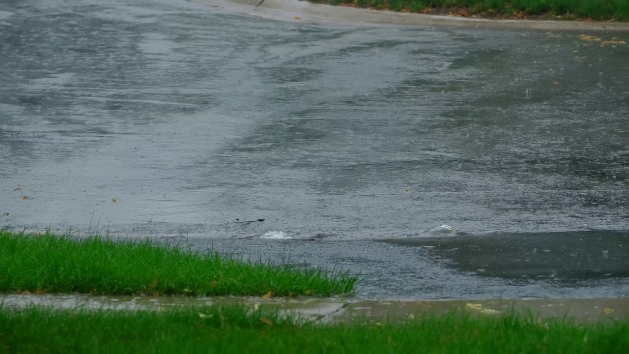 慢镜头，大雨落在柏油路的大水坑里，淹没了郊区的街道。缩放视图视频素材