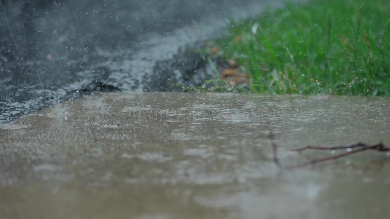 大雨落在柏油路上的大水坑里，淹没了郊区的街道。近距离视频素材