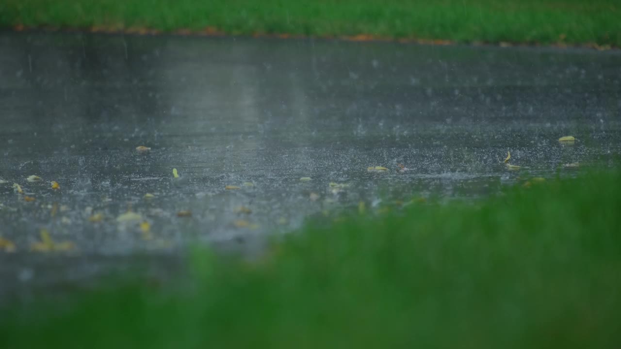 大雨落在柏油路上的大水坑里，淹没了郊区的街道。特写镜头视频素材