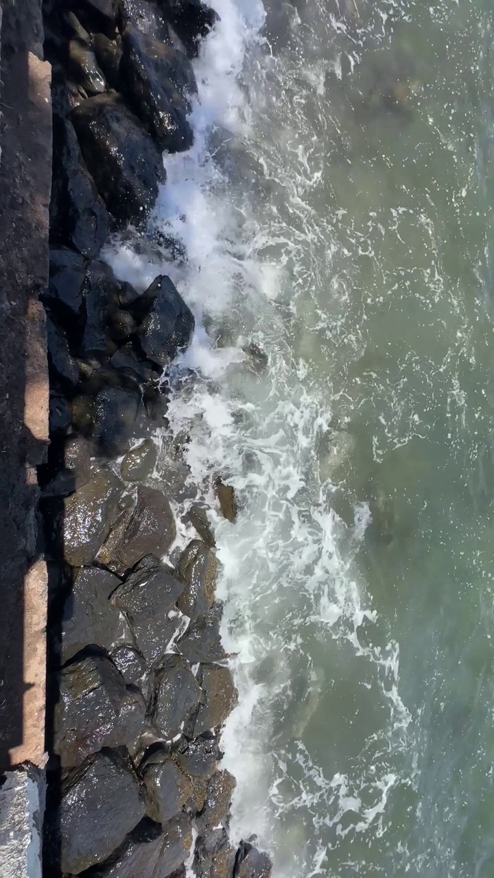 泡沫海浪粉碎海岸岩石的鸟瞰图视频素材