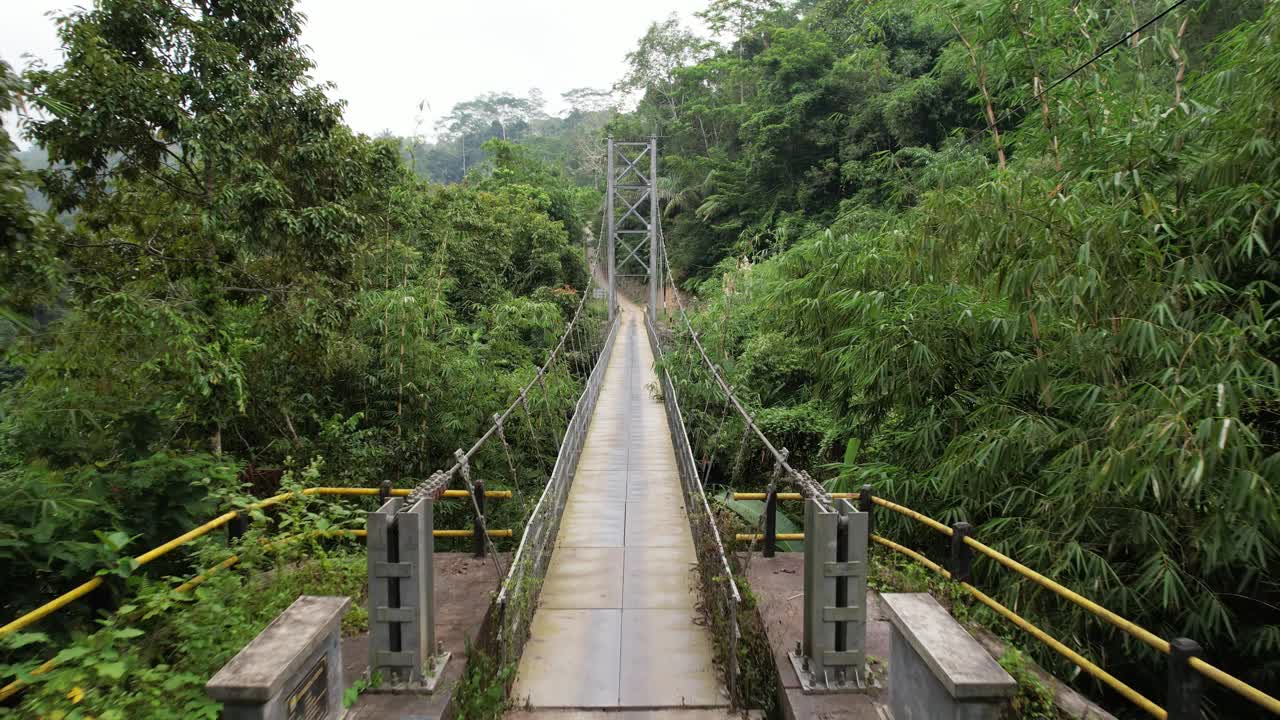 摄像机低空飞过横跨热带峡谷的不对称悬索桥视频素材