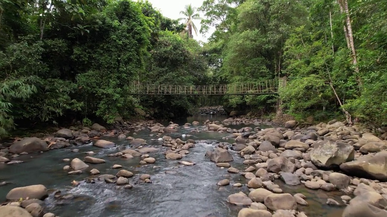 狭窄的吊桥横跨河流，当地人骑着摩托车经过视频素材