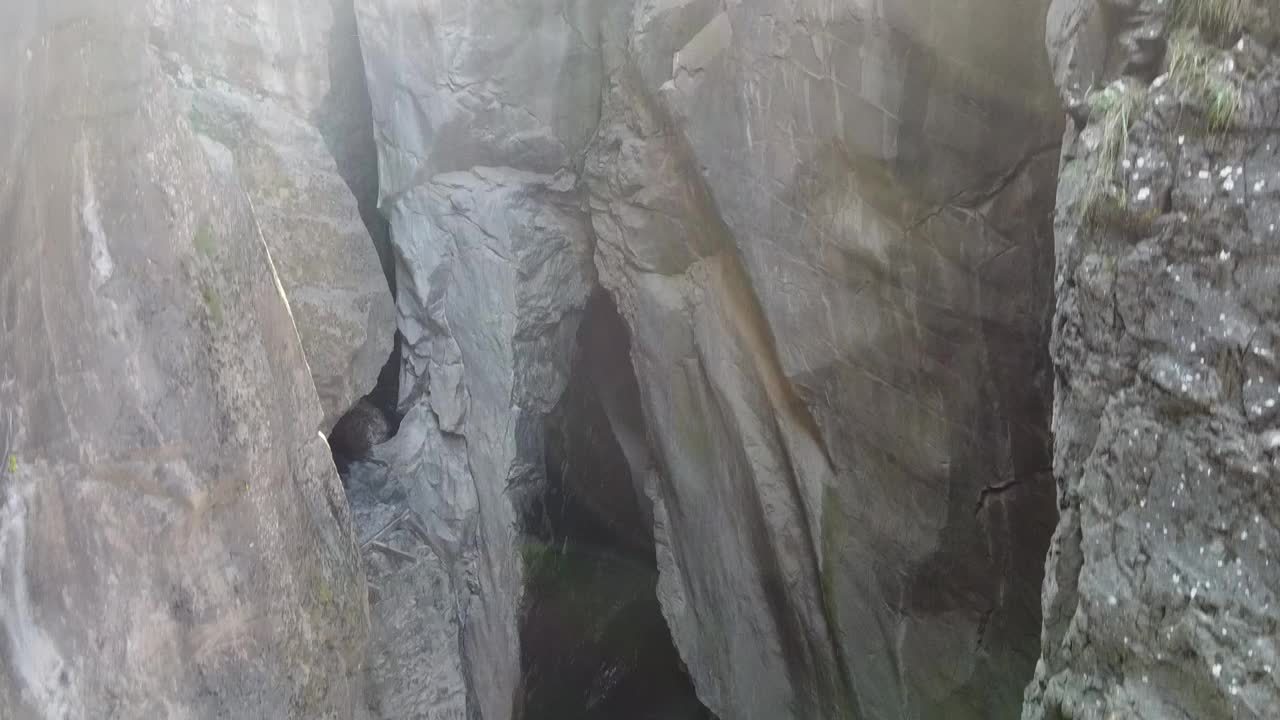 从空中降落到峡谷深处，瀑布从洞穴中倾泻而出视频素材