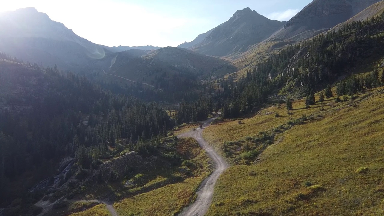 在砾石路上的空中，吉普车穿过科罗拉多山脉的大山谷视频素材