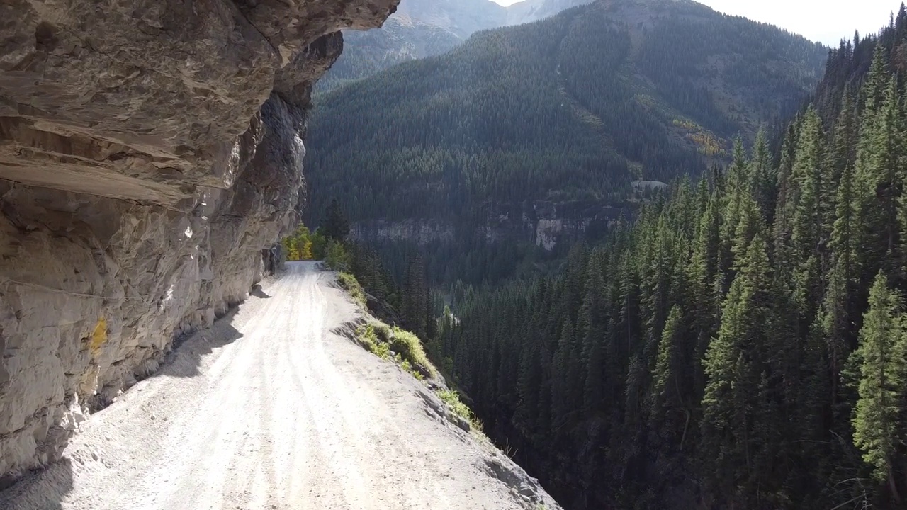 空中通过极其危险和狭窄的砾石路在悬崖边缘的山视频素材