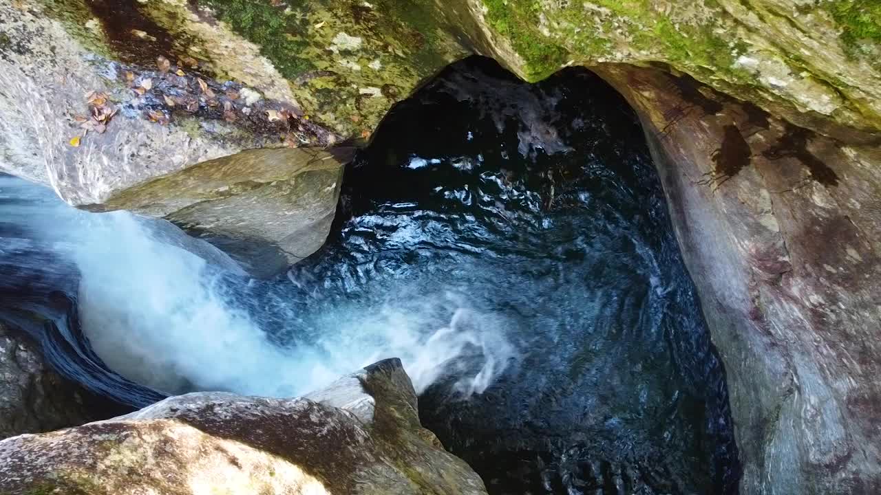 从空中俯瞰汹涌的急流，河流在两堵岩石墙之间漏斗状流动视频素材