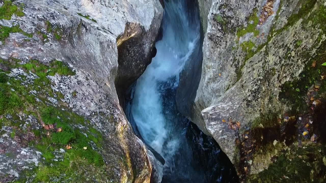 空中潘在岩石巨石峡谷内与小瀑布进入蓝色的水雕刻成悬崖周围的秋天树叶和苔藓视频素材