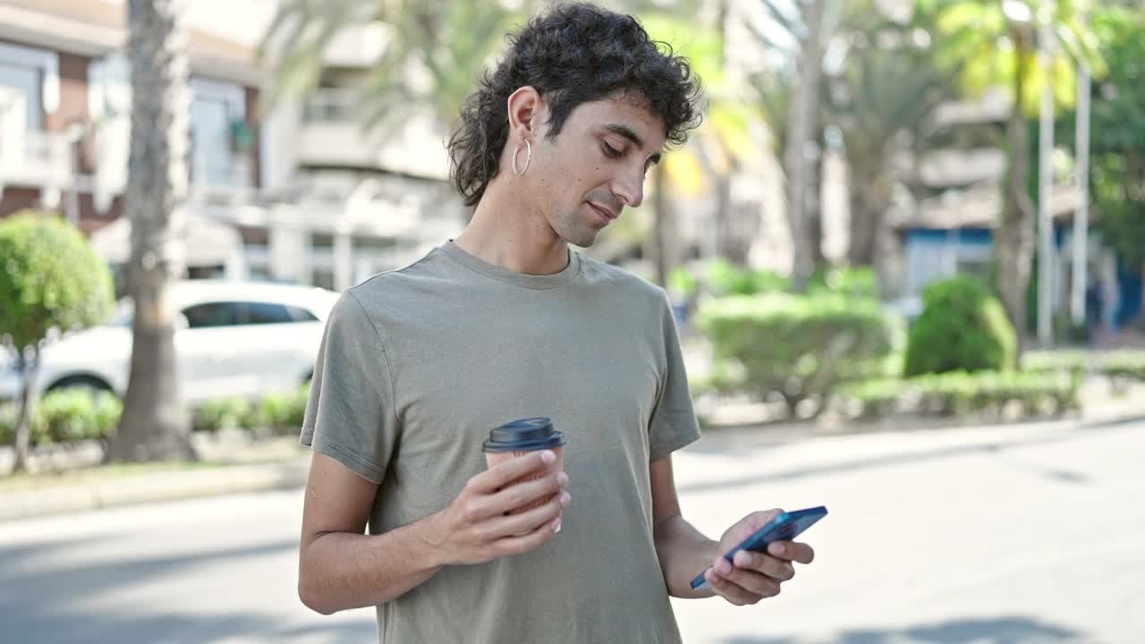 年轻的西班牙裔男子在街上用智能手机喝咖啡视频素材