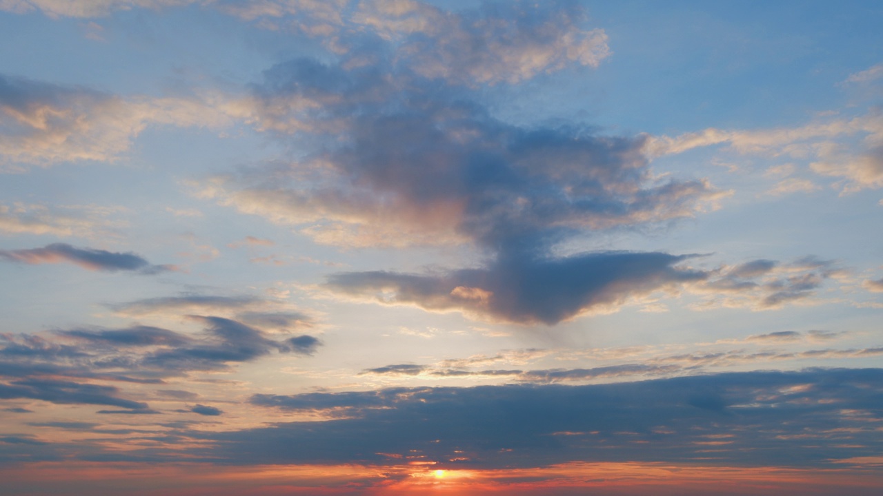 云彩在夕阳的映衬下划过天空。橘黄色的云在天空中流动。时间流逝。视频素材