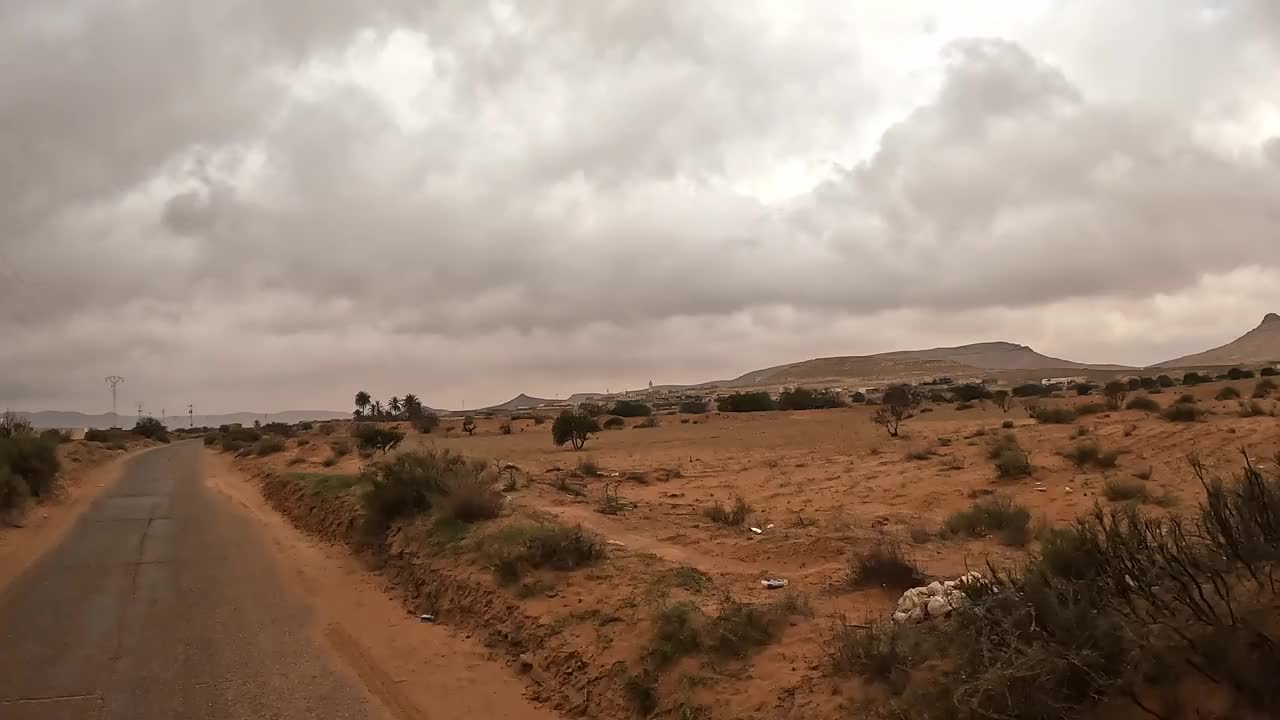 在多云的暴风雨天驾车穿过突尼斯干旱的风景，司机的视角视频素材