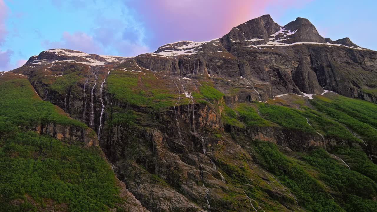 日落时，挪威盖朗格峡湾陡峭崎岖的雪山悬崖的低角度视图视频素材