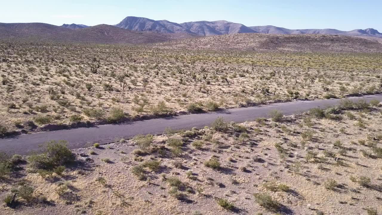 无人机拍摄的红色沙漠山脉。汽车行驶在沙漠山脉之间的道路上视频素材