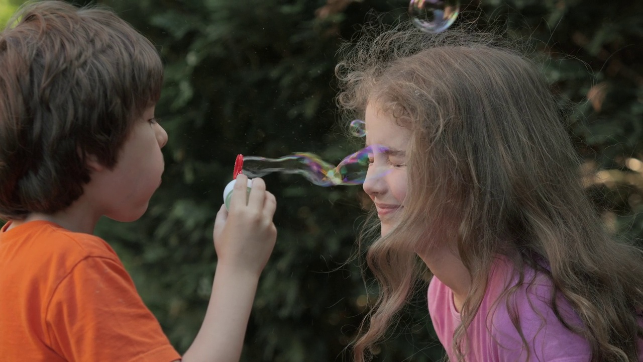 孩子们吹肥皂泡在户外玩耍，天真和好奇。男孩和女孩在公园，花园和大自然中吹肥皂泡，享受乐趣，快乐和儿童发展，自由视频素材