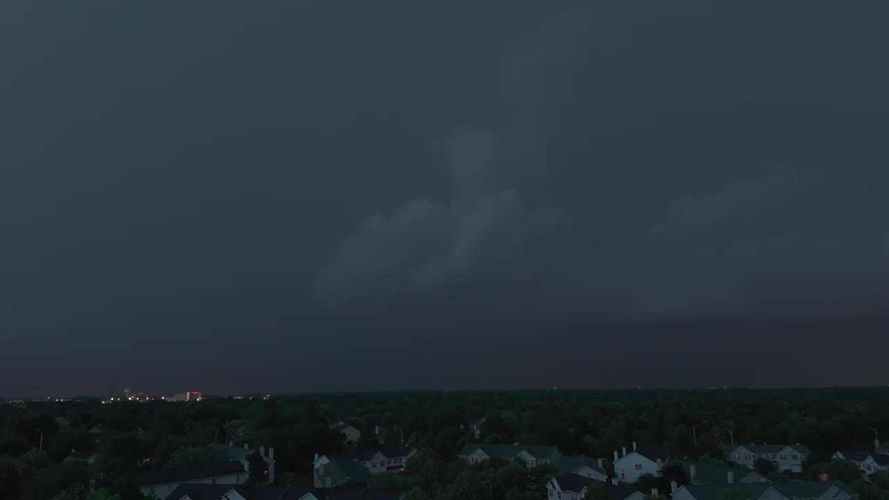 暴雨和闪电在郊区城镇地区之前，乌云在阴沉的天空中形成。广角无人机拍摄视频素材