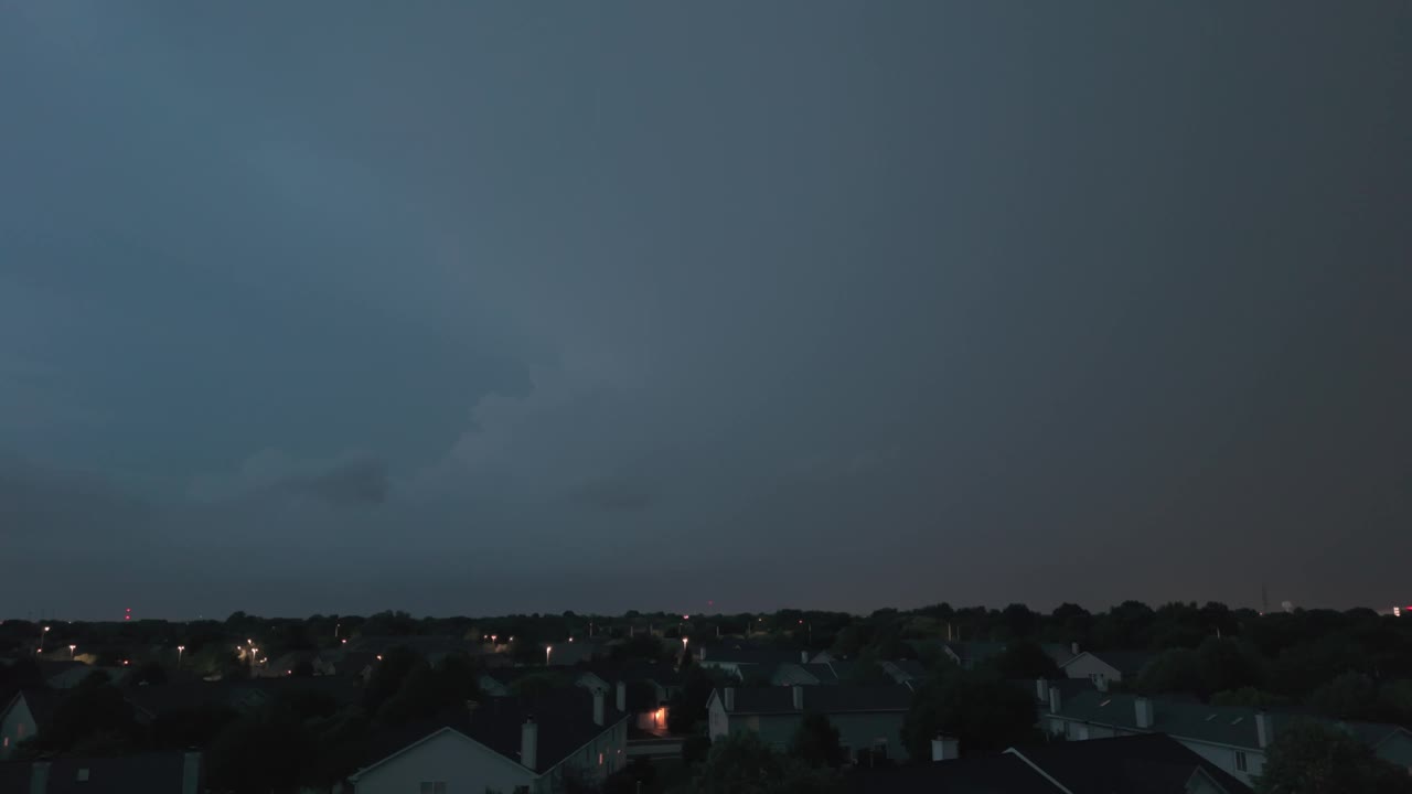 广角航拍的暴风雨云形成在阴暗的天空之前，大雨和闪电在郊区城镇地区。视频素材