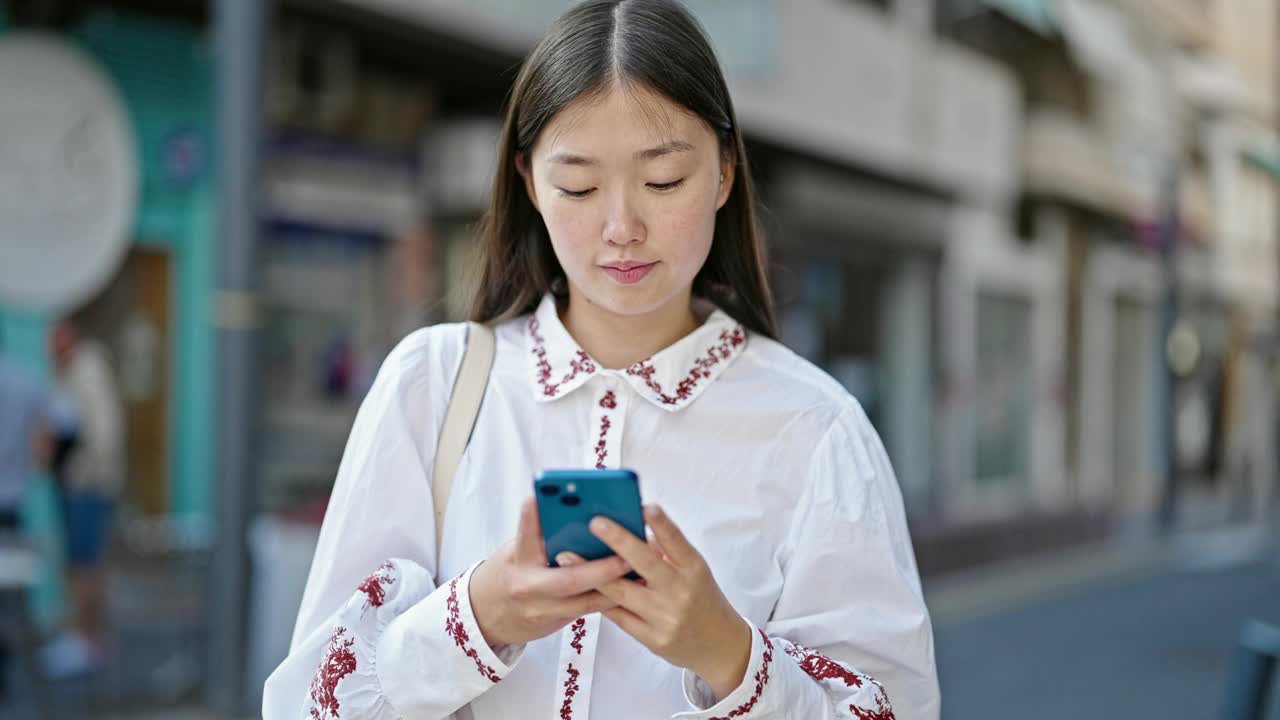 年轻的中国女子在街上用智能手机微笑视频素材