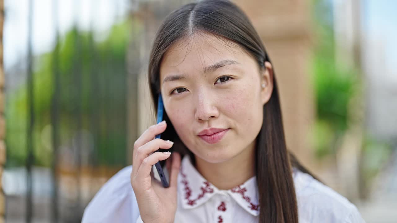 年轻的中国女子在街上用智能手机聊天视频素材