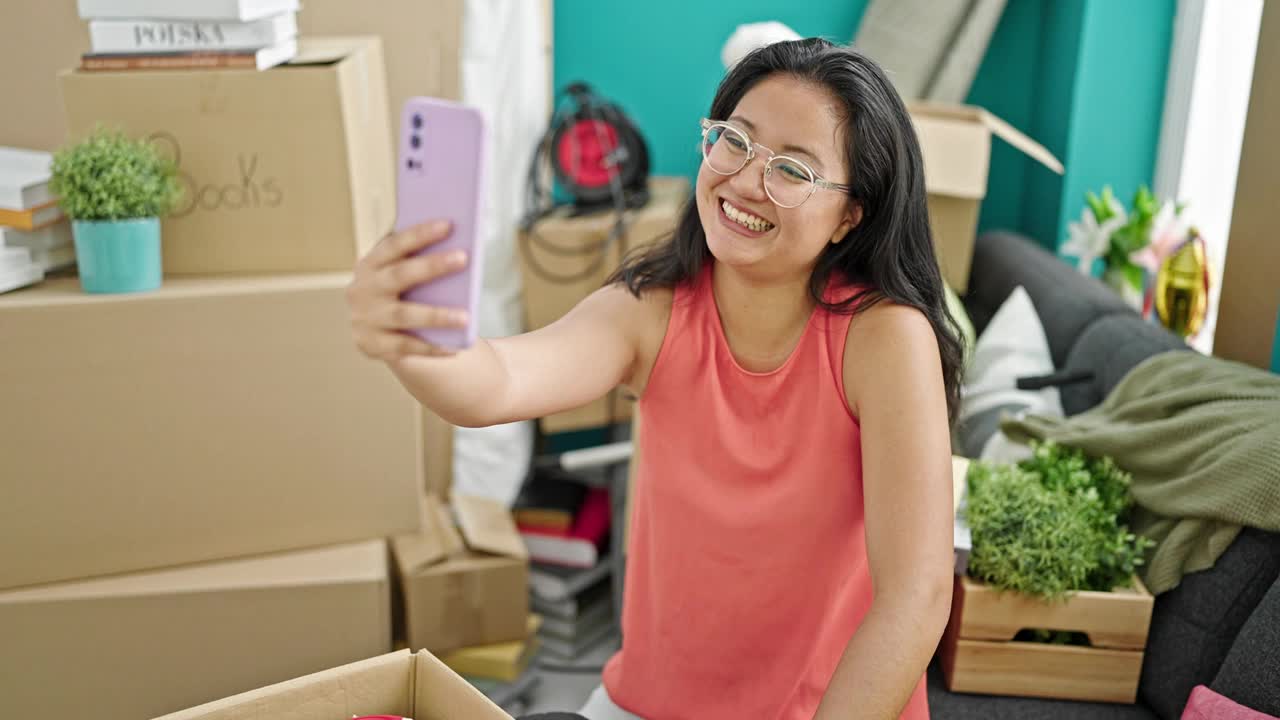 年轻的中国女子坐在新家的沙发上进行视频通话视频素材