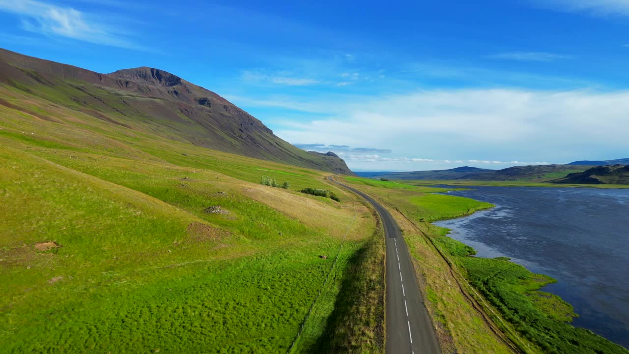 冰岛，鲸鱼峡湾(Hvalfjorour)的沥青公路上的无人机视图和蓝色多云的天空视频素材