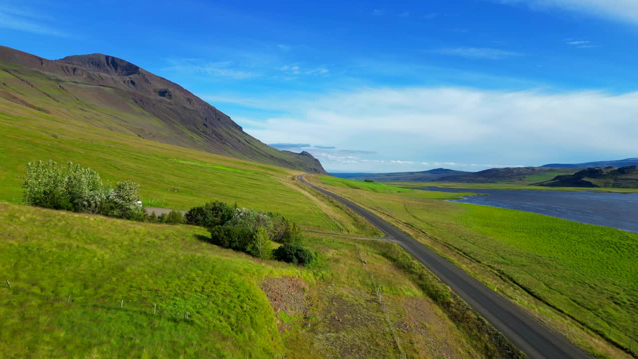 冰岛，鲸鱼峡湾(Hvalfjorour)的沥青公路上的无人机视图和蓝色多云的天空视频素材