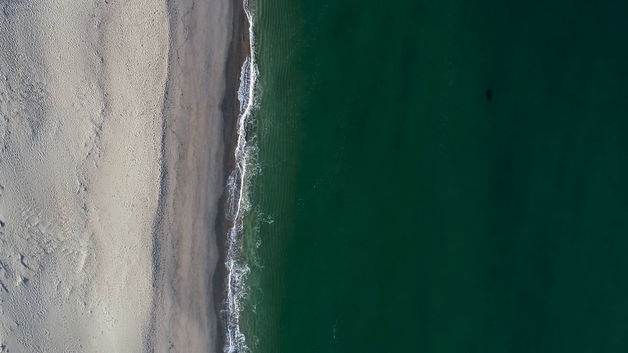 航拍的白色海滩，绿色的海水和波浪视频素材