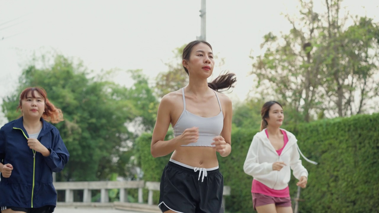 多种族团队年轻的亚洲运动女性穿着运动服，早上在家里的花园公园跑步。参加跑步俱乐部和户外运动。视频素材