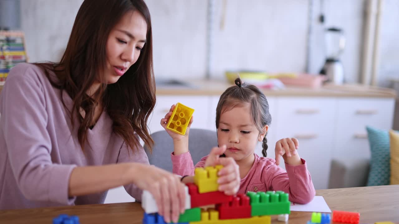 母亲和女儿在餐桌上玩积木视频素材