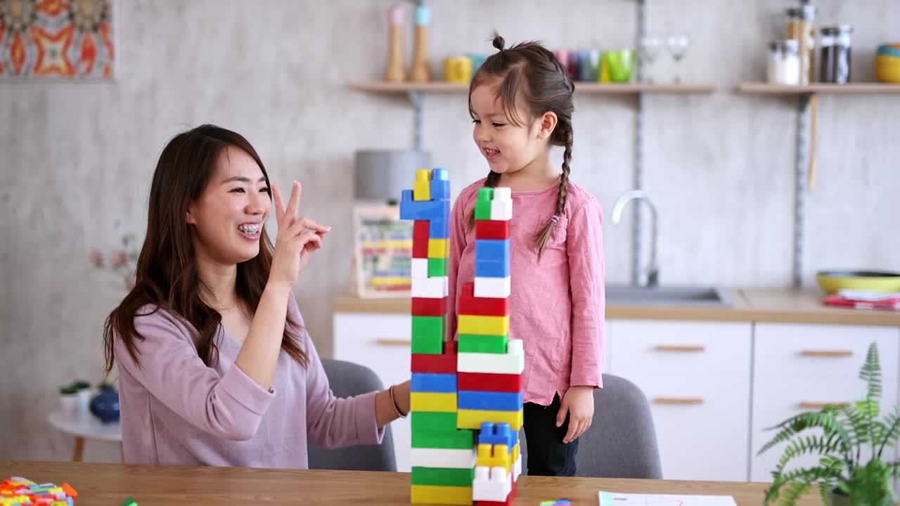 母亲和女儿在餐桌上玩积木视频素材