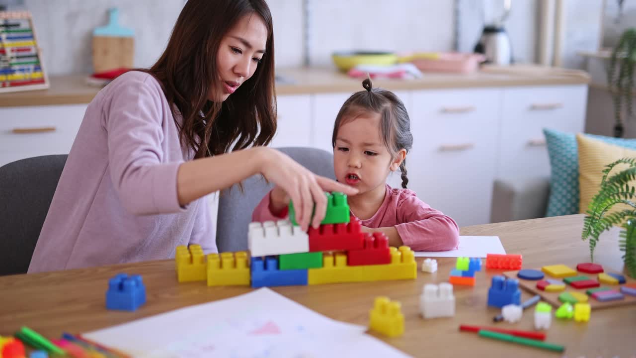 母亲和女儿在餐桌上玩积木视频素材