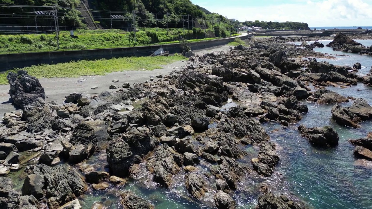 在阳光明媚的日子里，岩石海岸后面是狭窄的道路视频素材