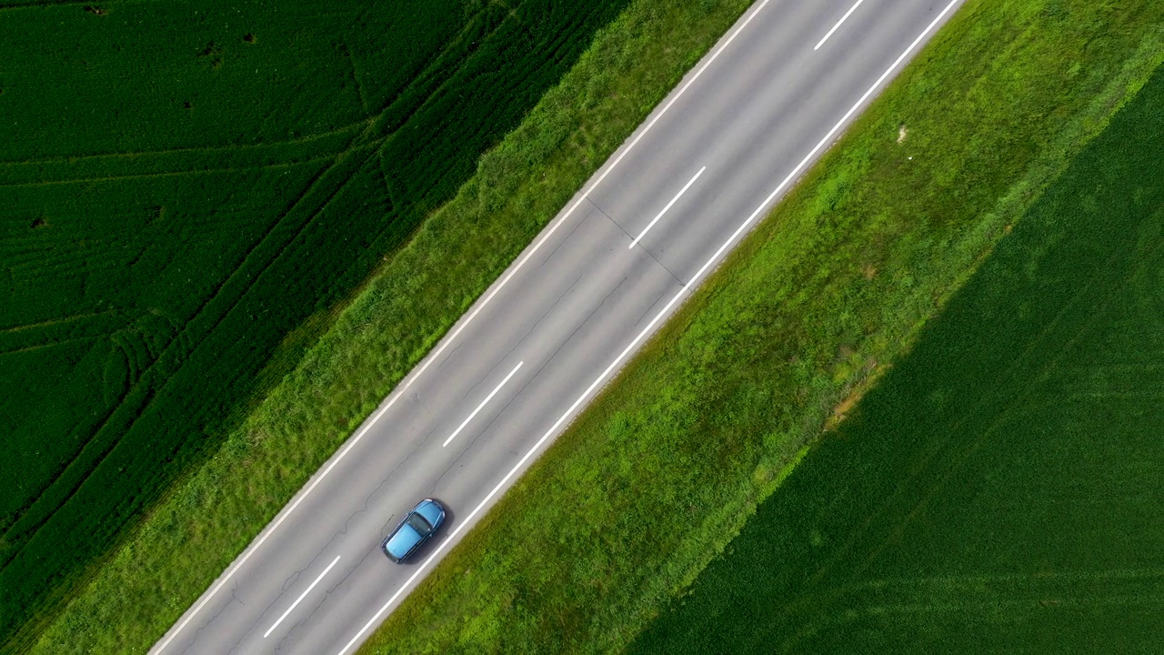 无人机拍摄的乡村道路交通全景。沿着公路行驶的汽车穿过开垦的景观。视频素材