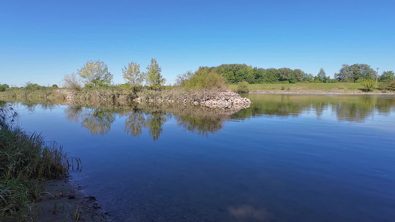 迷人的河流景观，河岸上的树木和水中的倒影视频素材