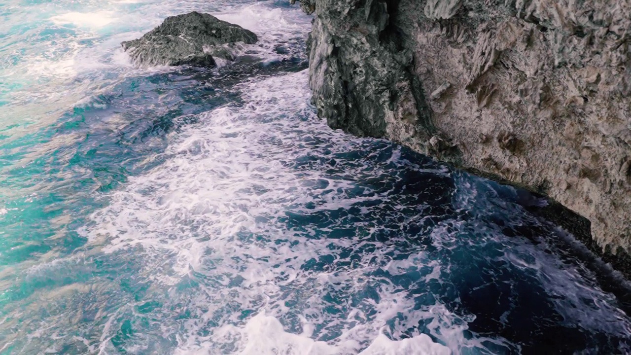 海浪撞击蓝色海水与大悬崖岩石的特写视频素材