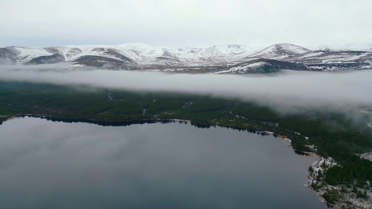 冬季景观，湖泊，绿色森林和雪山山脊的航拍镜头。低云或薄雾区分天气。英国苏格兰视频素材