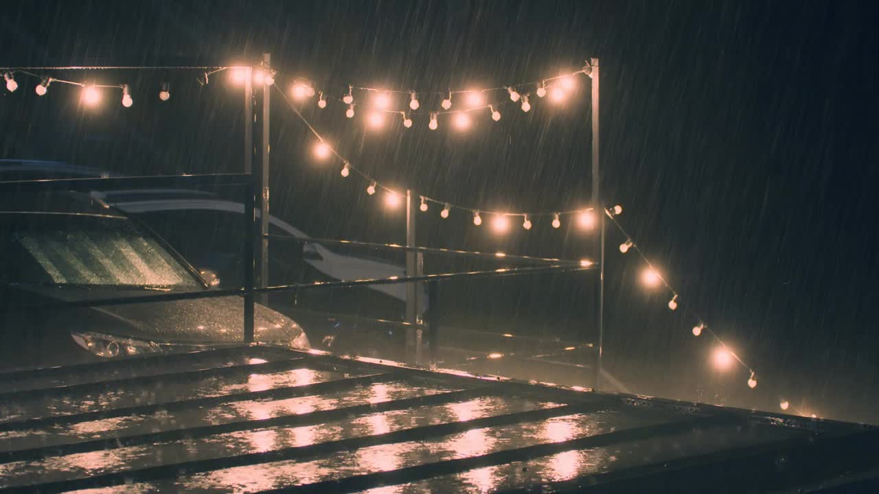 夜晚，暴雨落在露台的路灯上视频素材