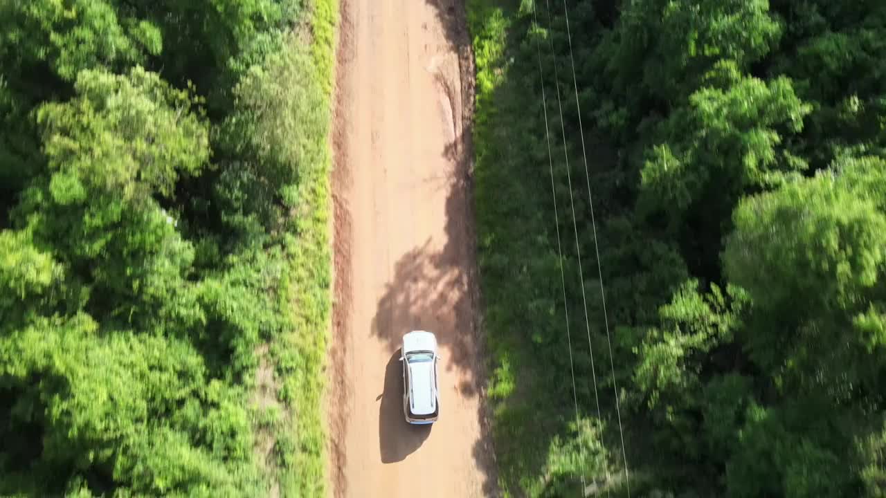 无人机自顶向下的视角跟踪越野车穿越热带丛林，沿途有电线视频素材