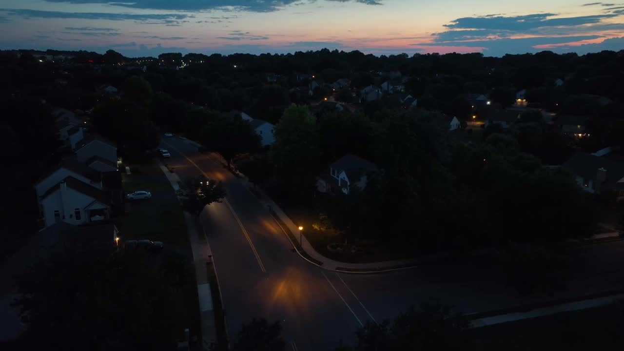 夜间在美国社区道路上行驶的汽车。黄昏时日落后的房屋航拍。视频素材