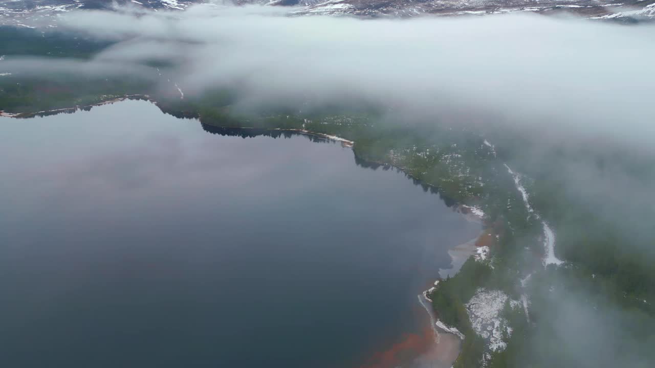 冬季山区景观的航拍电影镜头。平静的湖面和白雪皑皑的山脊。条纹的低云。英国苏格兰视频素材