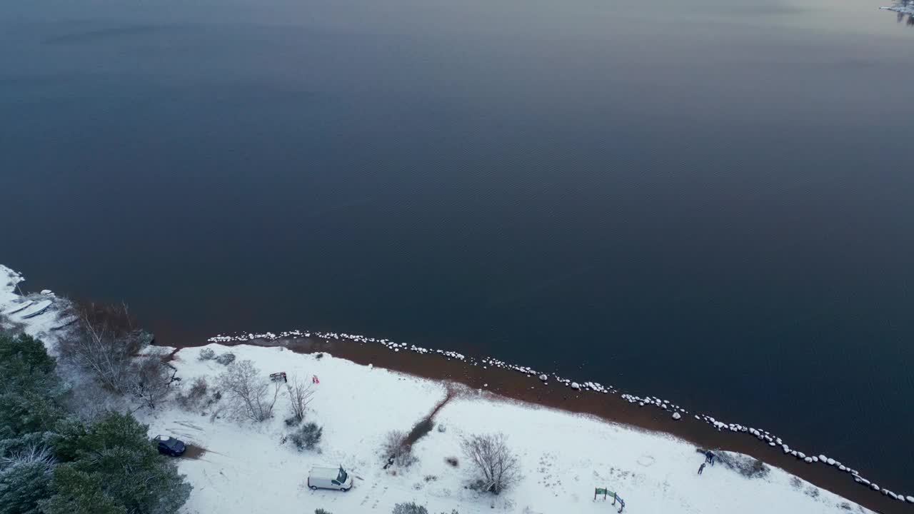 向前飞在冬天的风景之上。白雪覆盖的滨水，湖和丘陵乡村在对岸。英国苏格兰视频素材