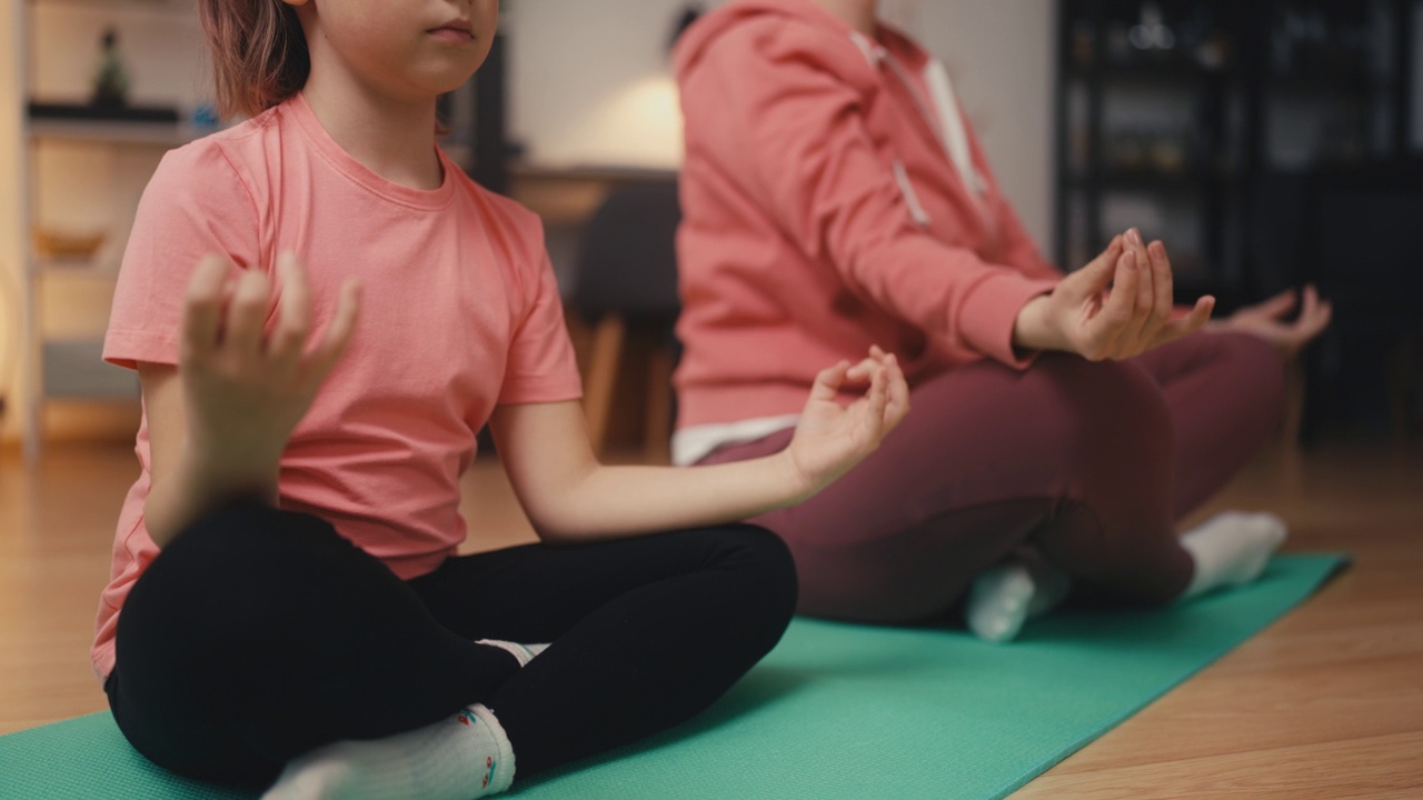 小女孩和妈妈坐在莲花式，一家人在练习瑜伽的特写视频素材