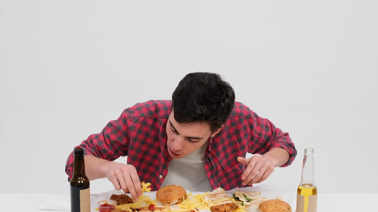 饥饿的白人男子在白色背景的餐桌上吃薯条视频素材