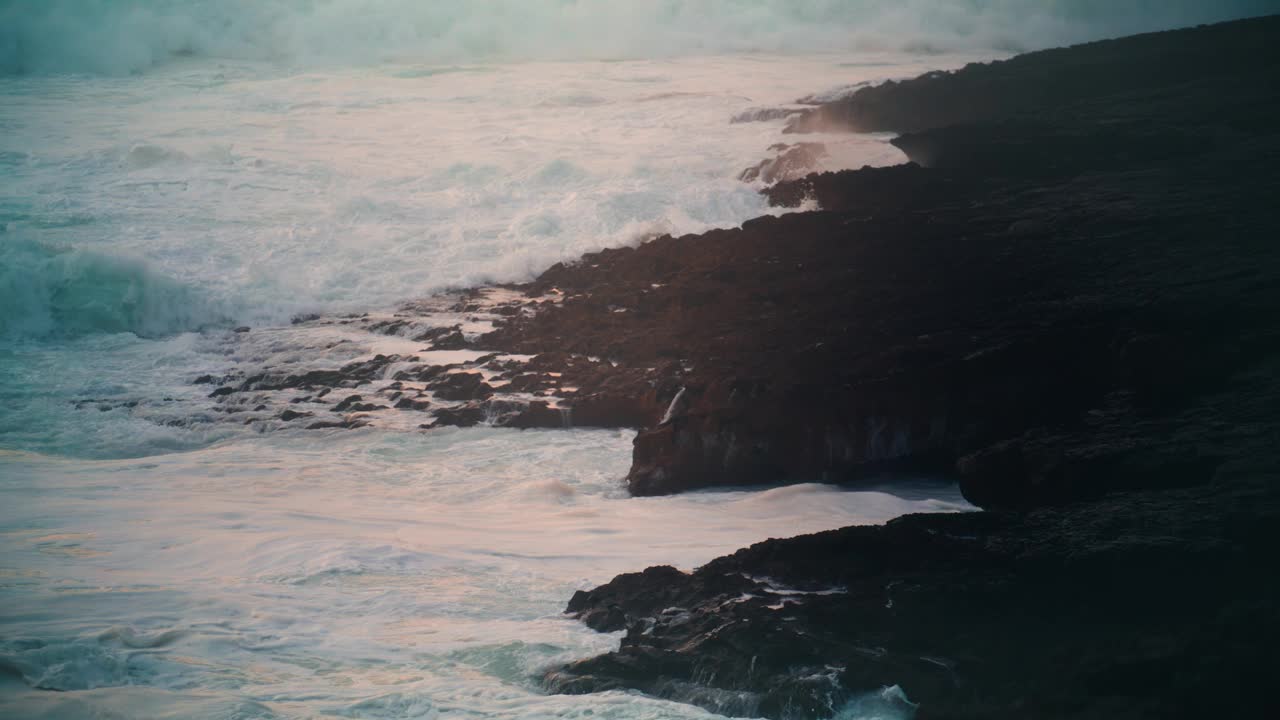 暴风雨的大海在傍晚袭击了多岩石的海岸线。巨浪翻滚破碎视频素材