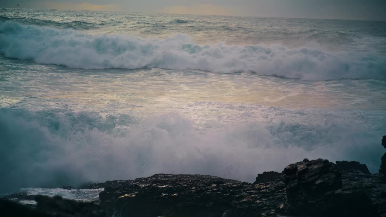 泡沫汹涌的海浪近距离打碎海岸线上的石头。强大的海洋翻滚的海岸视频素材